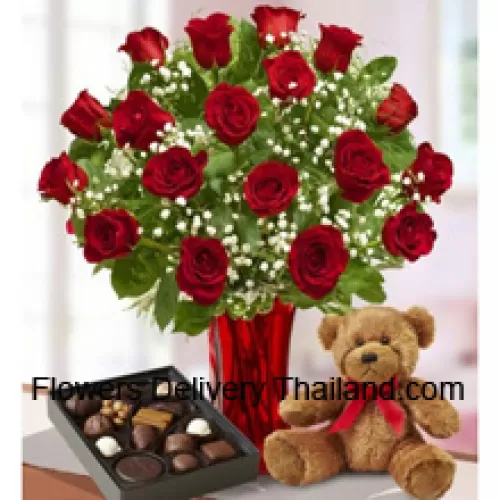 24 rote Rosen mit einigen Farnen in einer Glasvase, ein niedlicher brauner Teddybär und eine importierte Schachtel Schokoladen