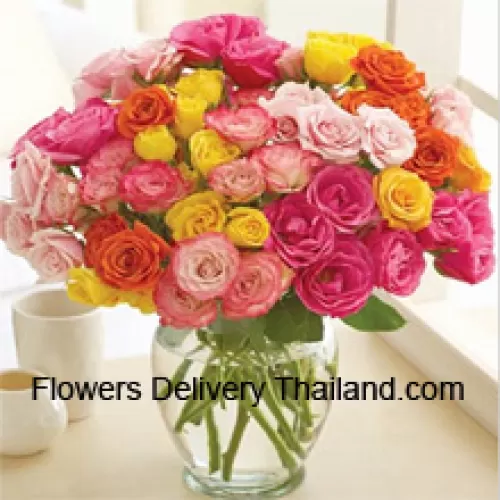 36 roses de différentes couleurs avec quelques fougères dans un vase en verre