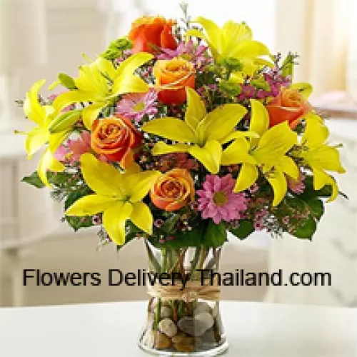 Lys jaunes, roses oranges et gerberas roses avec des remplisseurs saisonniers dans un vase en verre