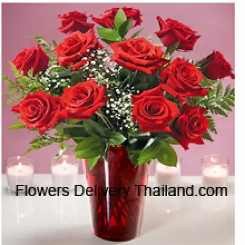 12 roses rouges avec quelques fougères dans un vase en verre
